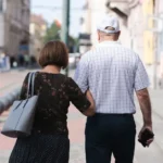 Senior couple walking arm-in-arm on a sunny urban street, capturing a moment of togetherness